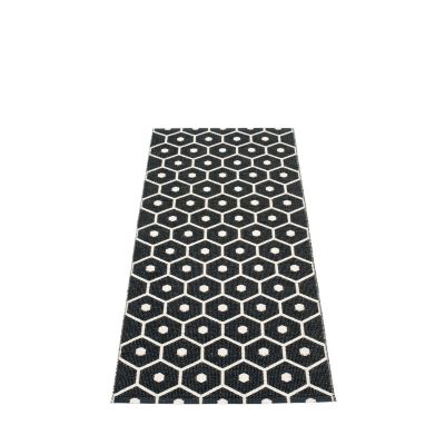 Pappelina Honey Kunststoffteppich 70x160 cm mit schwarzem Sechseckmuster und weißen Punkten. Moderner Teppich für Innen und Außen.